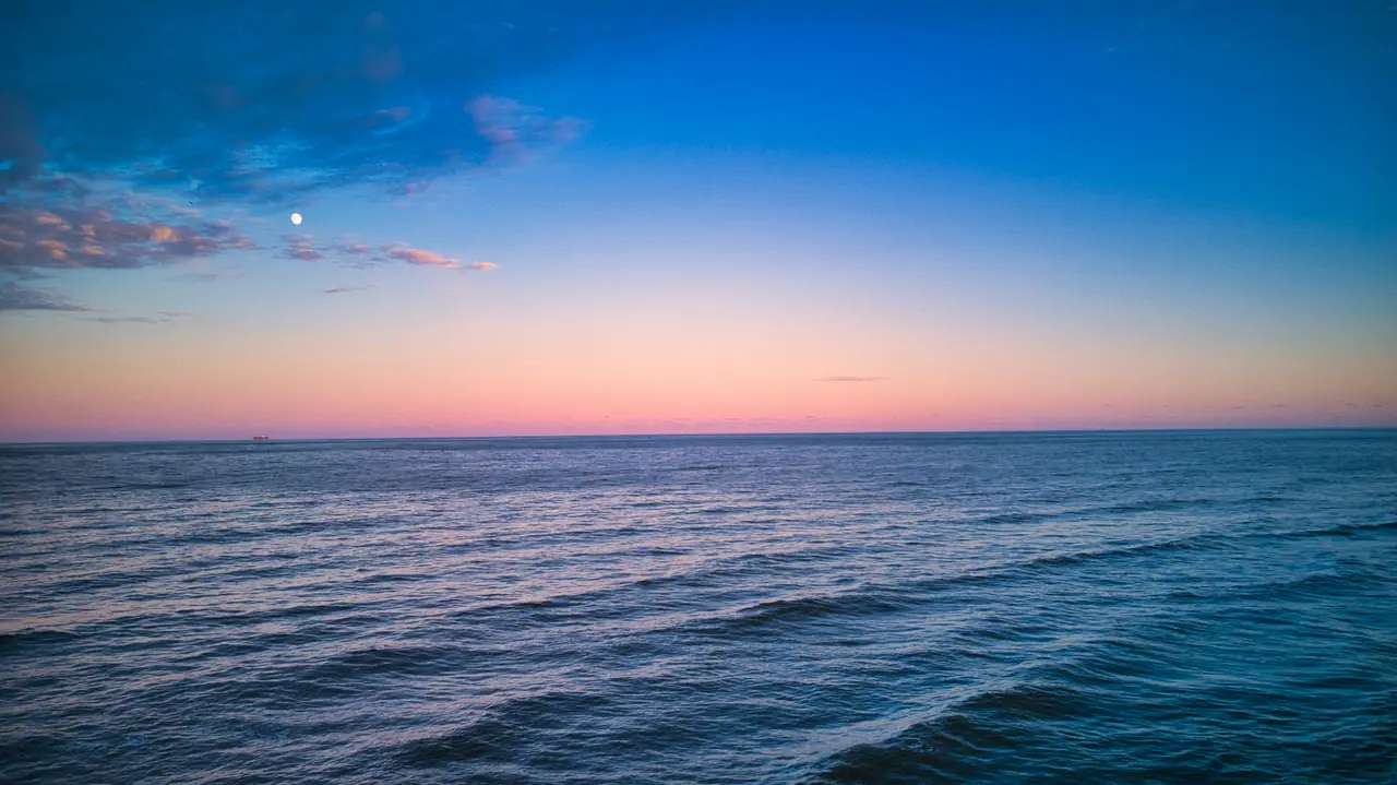 A calm sea at dusk, with the horizon in the distance